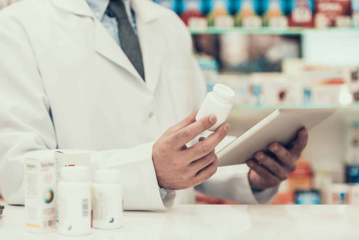 Closeup of a Pharmacist Holding Pills Bottle and Tablet.