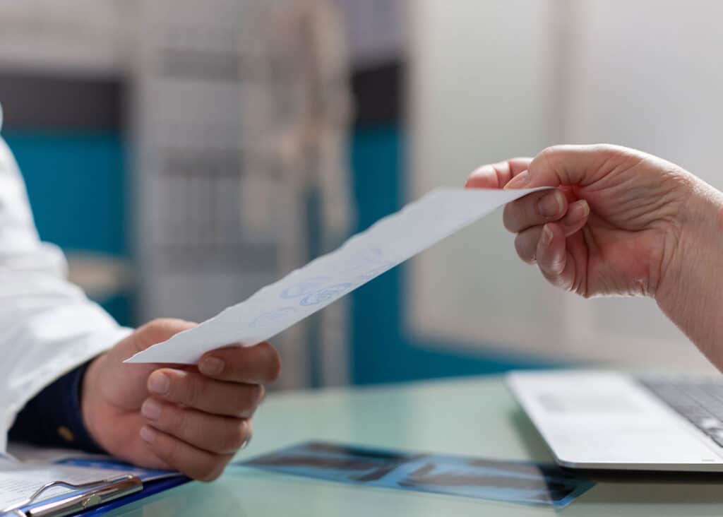 As they talk about prescription affordability, a doctor hands a prescription note to a patient.